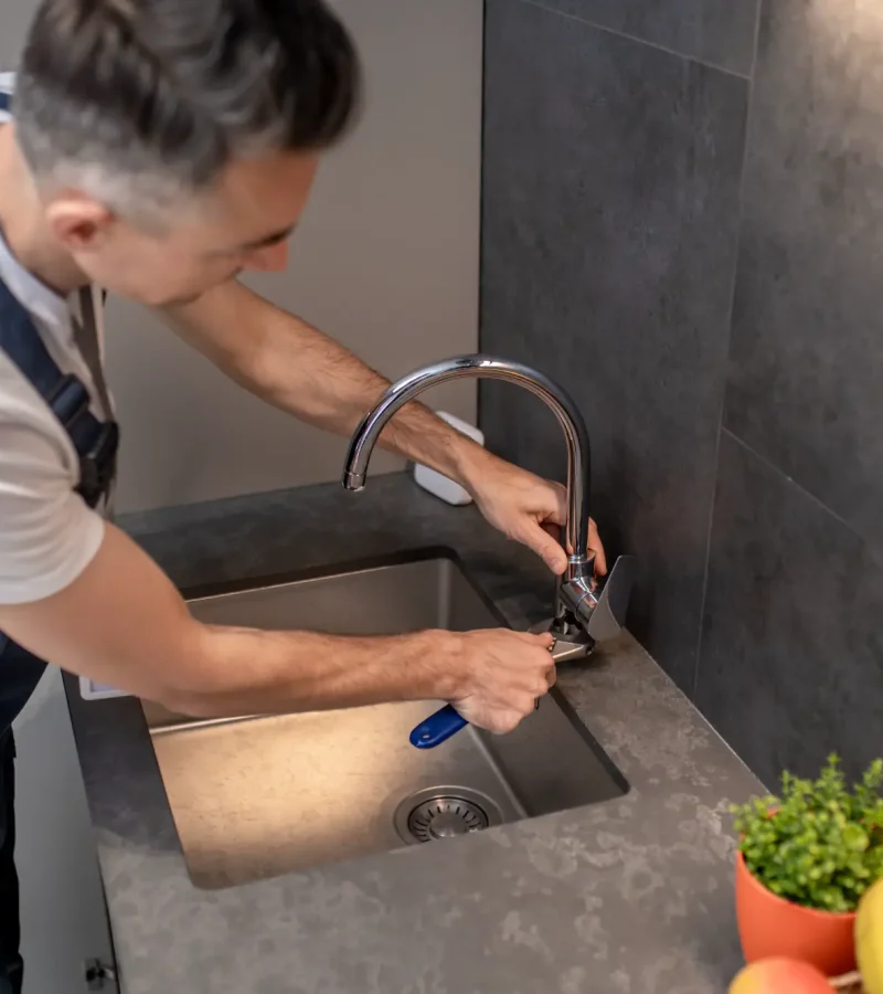 man-adjusting-water-tap-with-wrench